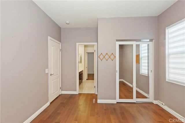 unfurnished bedroom with wood-type flooring and multiple windows