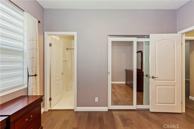 unfurnished bedroom featuring ensuite bathroom, a closet, and light wood-type flooring