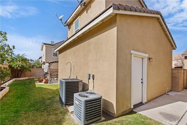 view of side of home with a patio, a yard, and central air condition unit