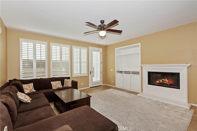 living room with built in shelves and ceiling fan