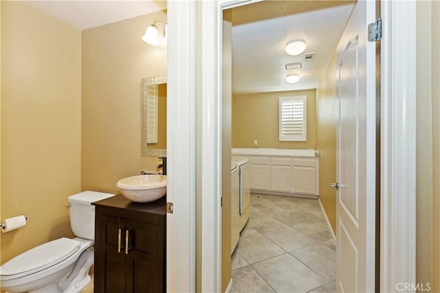 bathroom featuring separate washer and dryer, vanity, tile patterned floors, and toilet