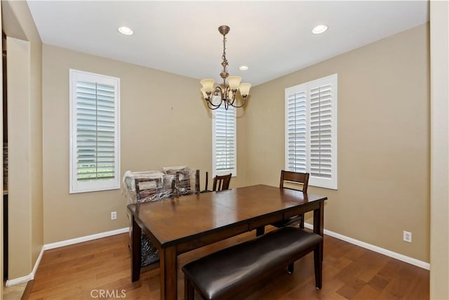 dining area featuring a healthy amount of sunlight, wood-type flooring, and a chandelier