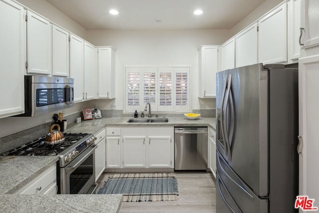 kitchen featuring stainless steel appliances, white cabinetry, sink, and light hardwood / wood-style flooring