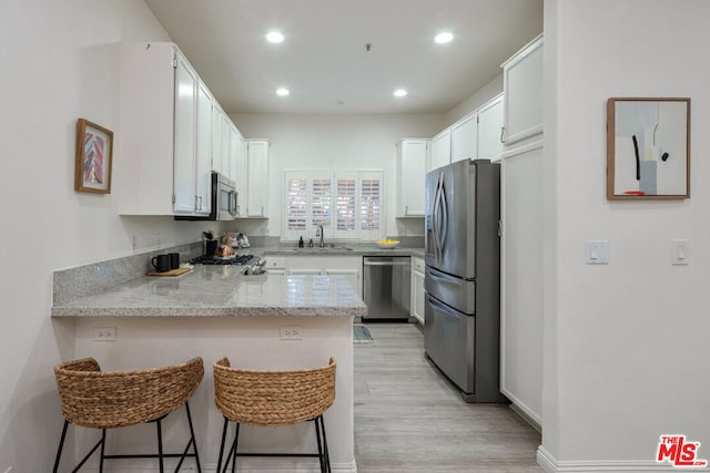 kitchen featuring white cabinetry, stainless steel appliances, a kitchen breakfast bar, and kitchen peninsula