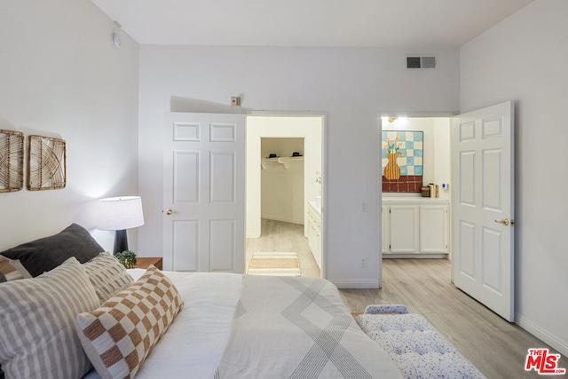 bedroom featuring connected bathroom and light hardwood / wood-style flooring