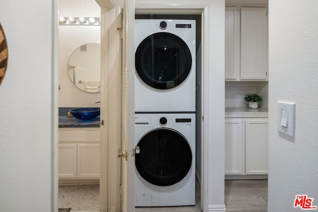 clothes washing area with stacked washing maching and dryer and sink