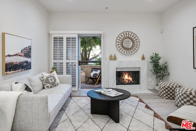 living room with a high end fireplace and light hardwood / wood-style floors