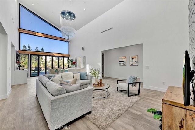 living room featuring a chandelier, high vaulted ceiling, and light hardwood / wood-style floors