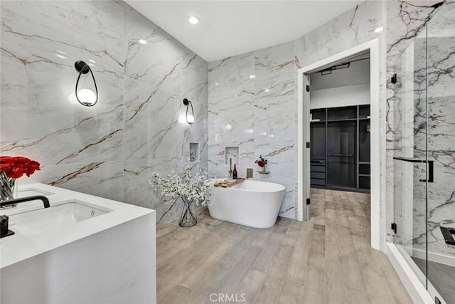 bathroom with vanity, hardwood / wood-style floors, tile walls, and separate shower and tub