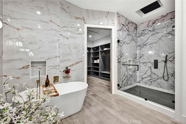 bathroom with hardwood / wood-style flooring, shower with separate bathtub, and tile walls