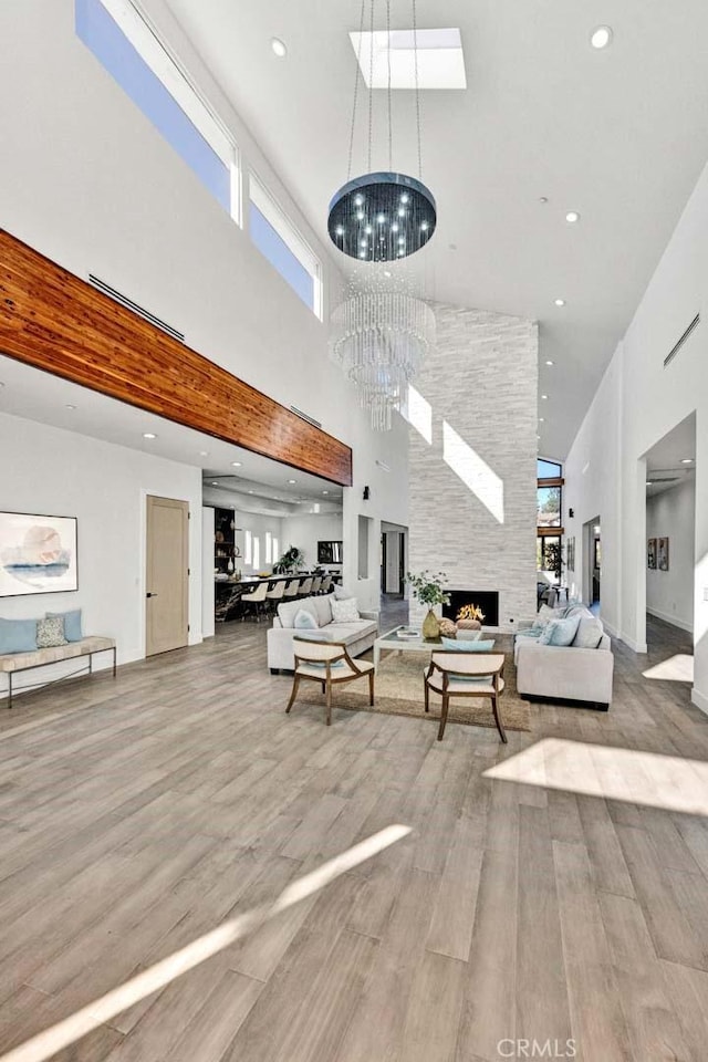 living room with an inviting chandelier, hardwood / wood-style flooring, a fireplace, and a high ceiling