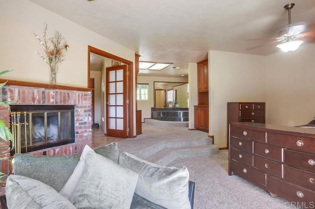 living room featuring a brick fireplace, light carpet, and ceiling fan