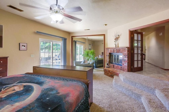 carpeted bedroom with ceiling fan, a brick fireplace, and a closet