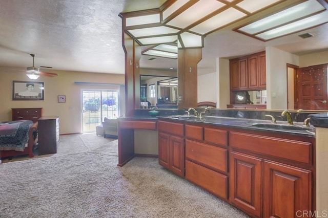 kitchen with ceiling fan, light colored carpet, sink, and a textured ceiling