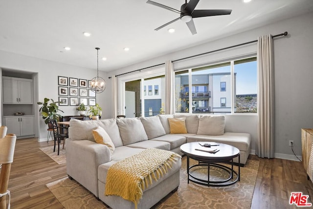 living room featuring dark wood-type flooring and ceiling fan with notable chandelier