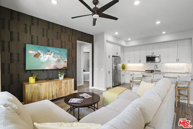 living room featuring sink, wood-type flooring, and ceiling fan