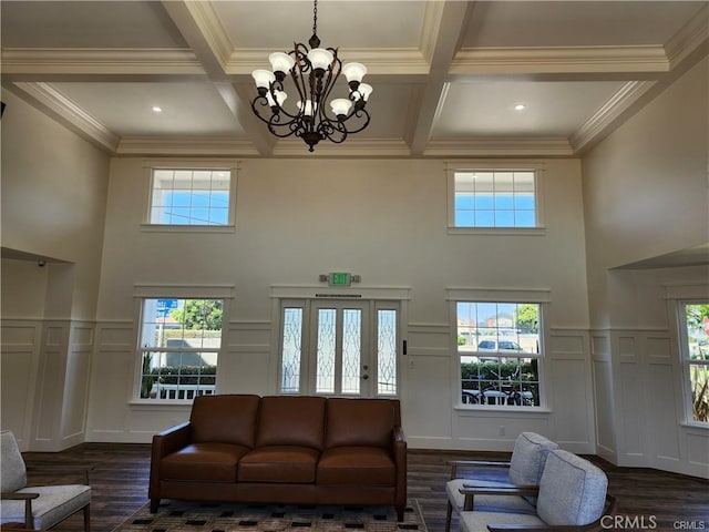 living room featuring crown molding, dark wood-type flooring, beam ceiling, coffered ceiling, and a notable chandelier