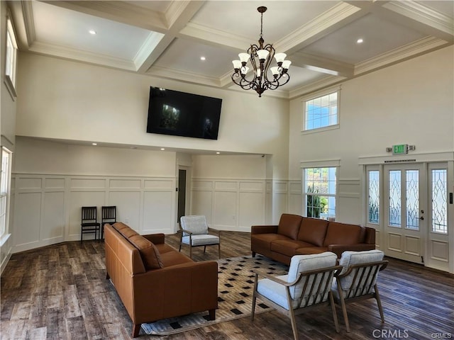 living room with coffered ceiling, ornamental molding, dark hardwood / wood-style flooring, a notable chandelier, and beamed ceiling