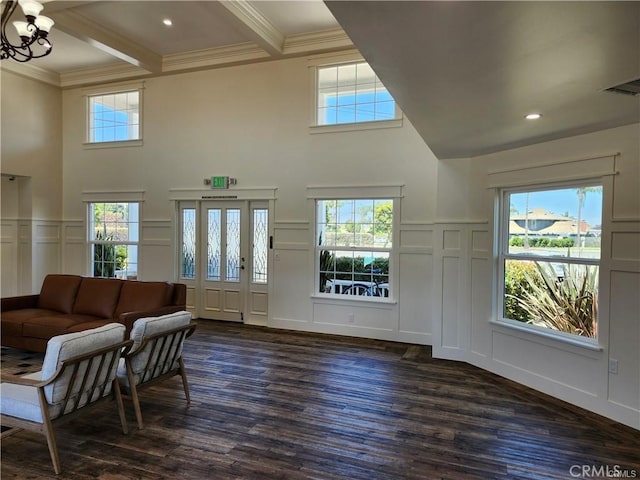 living room with beamed ceiling, ornamental molding, dark hardwood / wood-style floors, and a chandelier