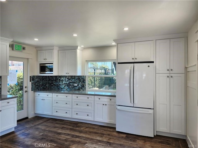 kitchen featuring white cabinetry, stainless steel microwave, dark hardwood / wood-style flooring, white fridge, and decorative backsplash