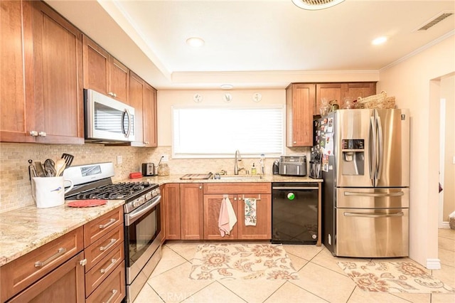 kitchen featuring tasteful backsplash, appliances with stainless steel finishes, sink, and light stone counters