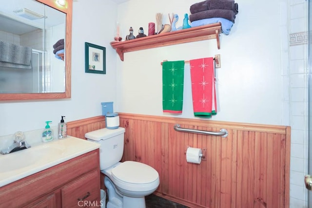 bathroom featuring vanity, wooden walls, and toilet