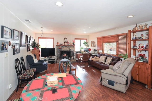 living room featuring a stone fireplace and dark hardwood / wood-style flooring