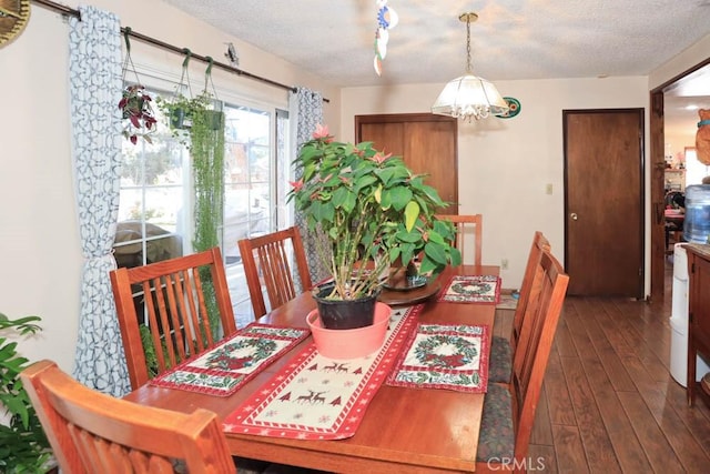 dining room featuring dark wood-type flooring and a textured ceiling