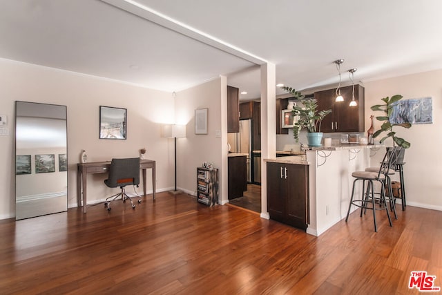 kitchen featuring dark hardwood / wood-style flooring, a kitchen bar, dark brown cabinetry, kitchen peninsula, and light stone countertops