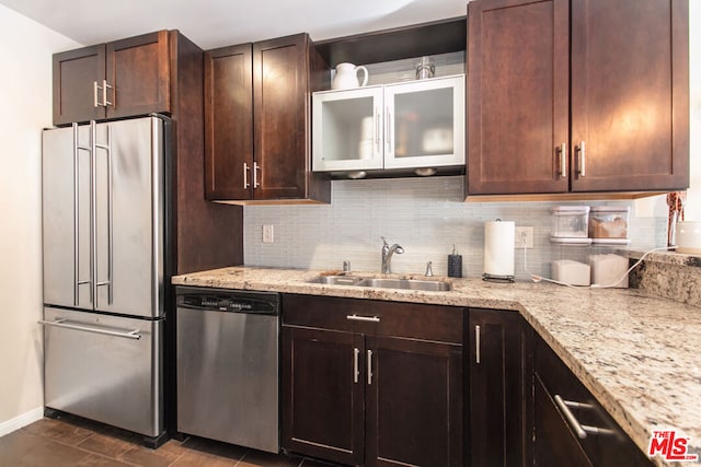 kitchen featuring tasteful backsplash, sink, dark tile patterned flooring, stainless steel appliances, and light stone countertops