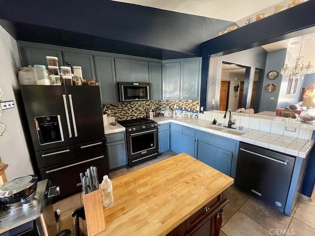 kitchen with sink, dishwasher, high end stainless steel range oven, backsplash, and black refrigerator with ice dispenser