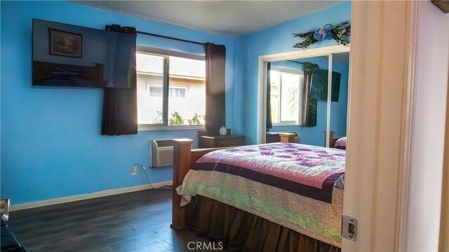 bedroom featuring dark wood-type flooring and a wall mounted AC