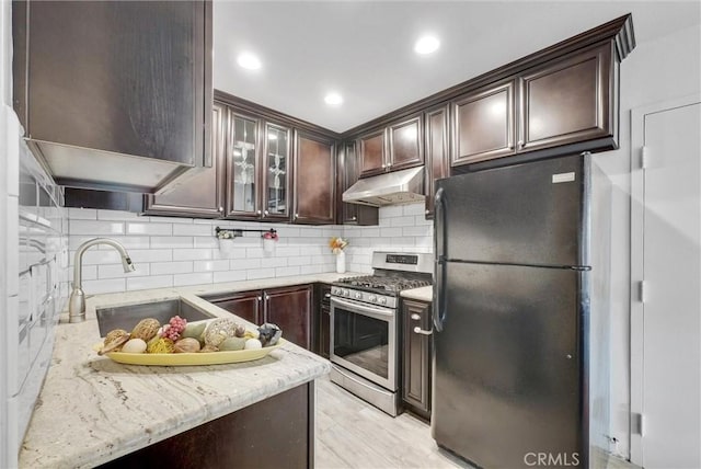 kitchen with black fridge, sink, gas stove, and dark brown cabinets