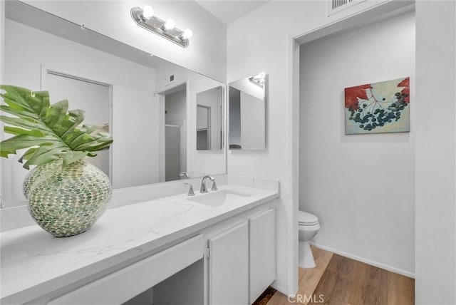 bathroom with hardwood / wood-style flooring, vanity, an enclosed shower, and toilet