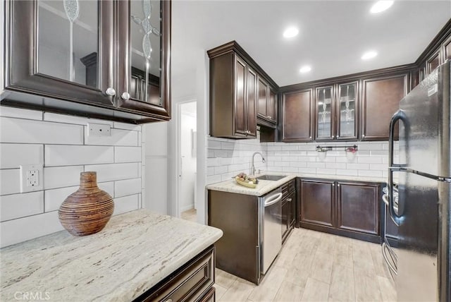 kitchen featuring black refrigerator, tasteful backsplash, sink, stainless steel dishwasher, and light stone countertops