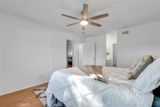 bedroom with wood-type flooring, ceiling fan, and ensuite bath