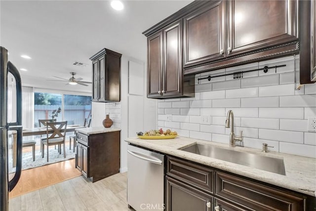 kitchen featuring dark brown cabinetry, sink, black fridge, dishwasher, and decorative backsplash