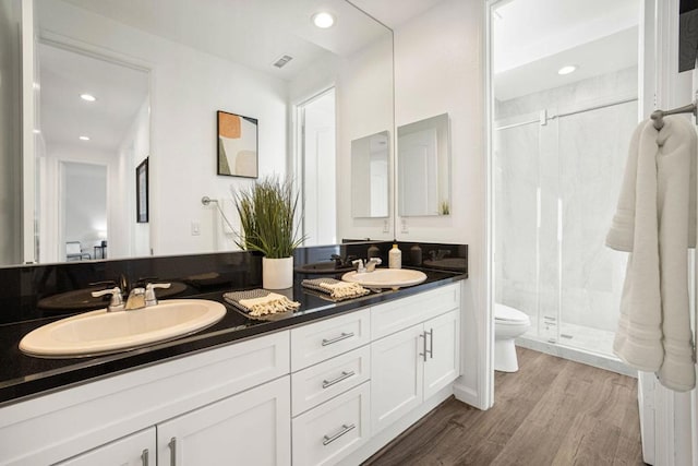 bathroom featuring hardwood / wood-style flooring, vanity, toilet, and a shower with shower door