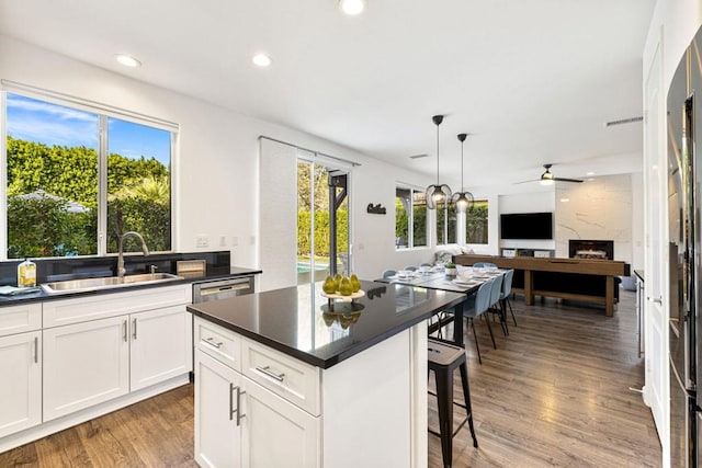 kitchen with sink, white cabinetry, a center island, hanging light fixtures, and hardwood / wood-style floors