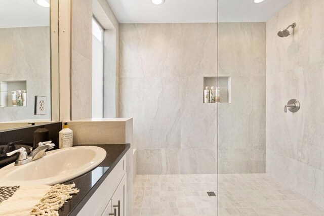 bathroom with vanity, tile walls, and tiled shower