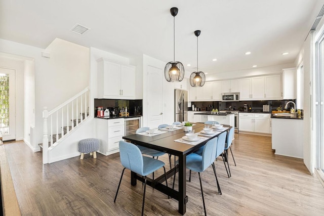 dining space featuring wine cooler, sink, and light wood-type flooring