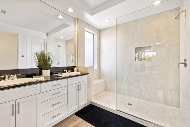 bathroom with hardwood / wood-style flooring, vanity, and a tile shower