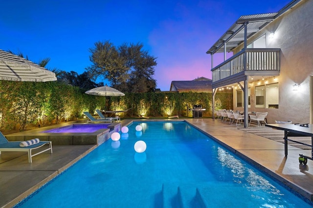 pool at dusk with a patio area and an in ground hot tub