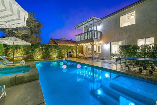 pool at dusk with an in ground hot tub, area for grilling, and a patio area