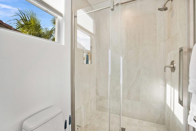 bathroom with a shower with door and toilet