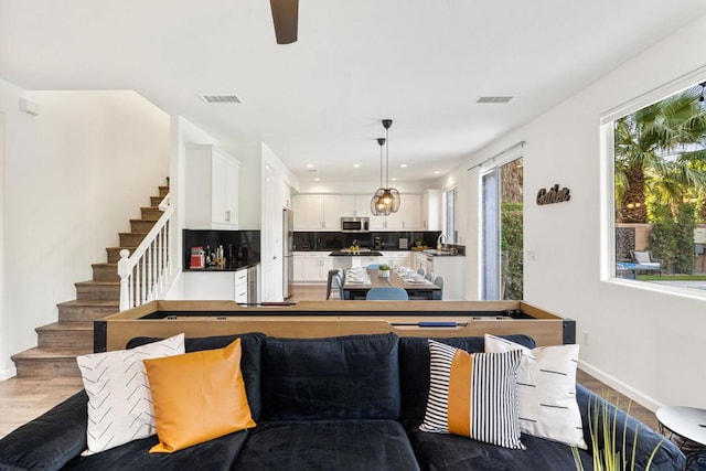 kitchen featuring white cabinetry, appliances with stainless steel finishes, pendant lighting, hardwood / wood-style floors, and decorative backsplash