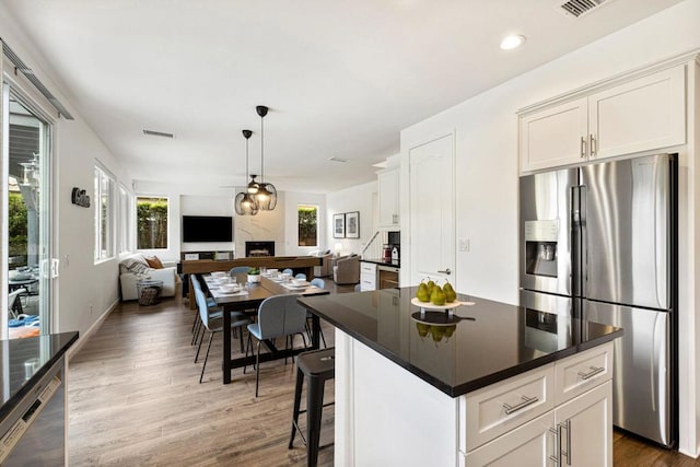 kitchen with white cabinetry, appliances with stainless steel finishes, decorative light fixtures, and a center island