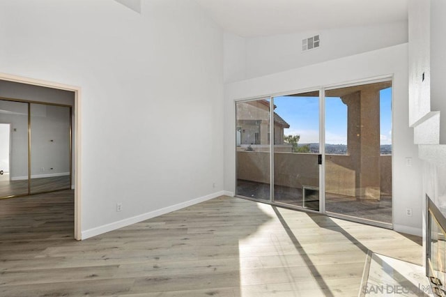 unfurnished room featuring lofted ceiling and light hardwood / wood-style flooring