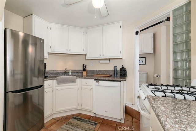 kitchen with sink, white appliances, light tile patterned floors, ceiling fan, and white cabinets