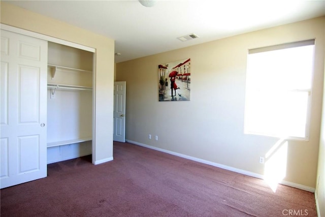 unfurnished bedroom with dark carpet and a closet